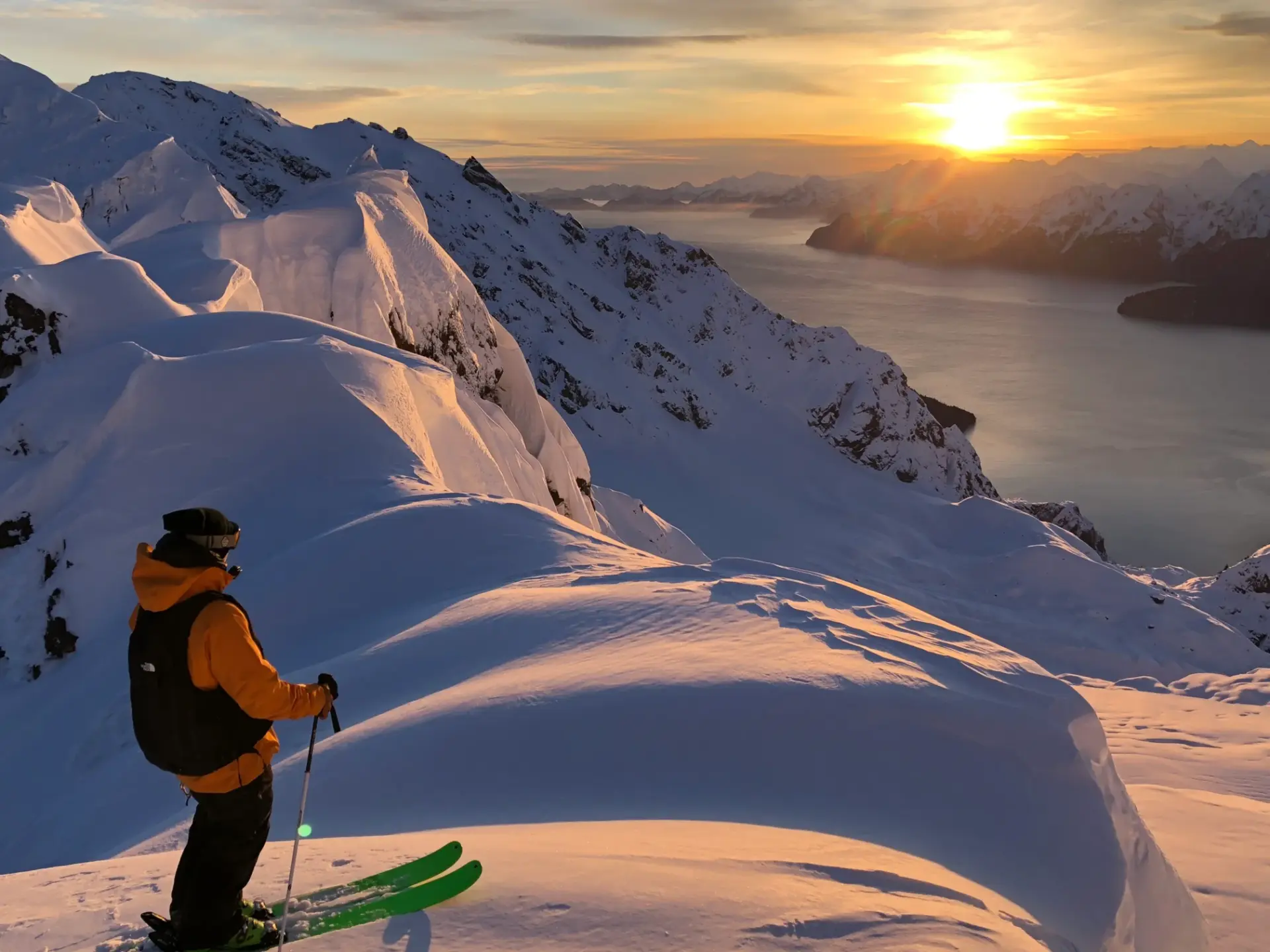 Skier overlooking the fjords at sunset