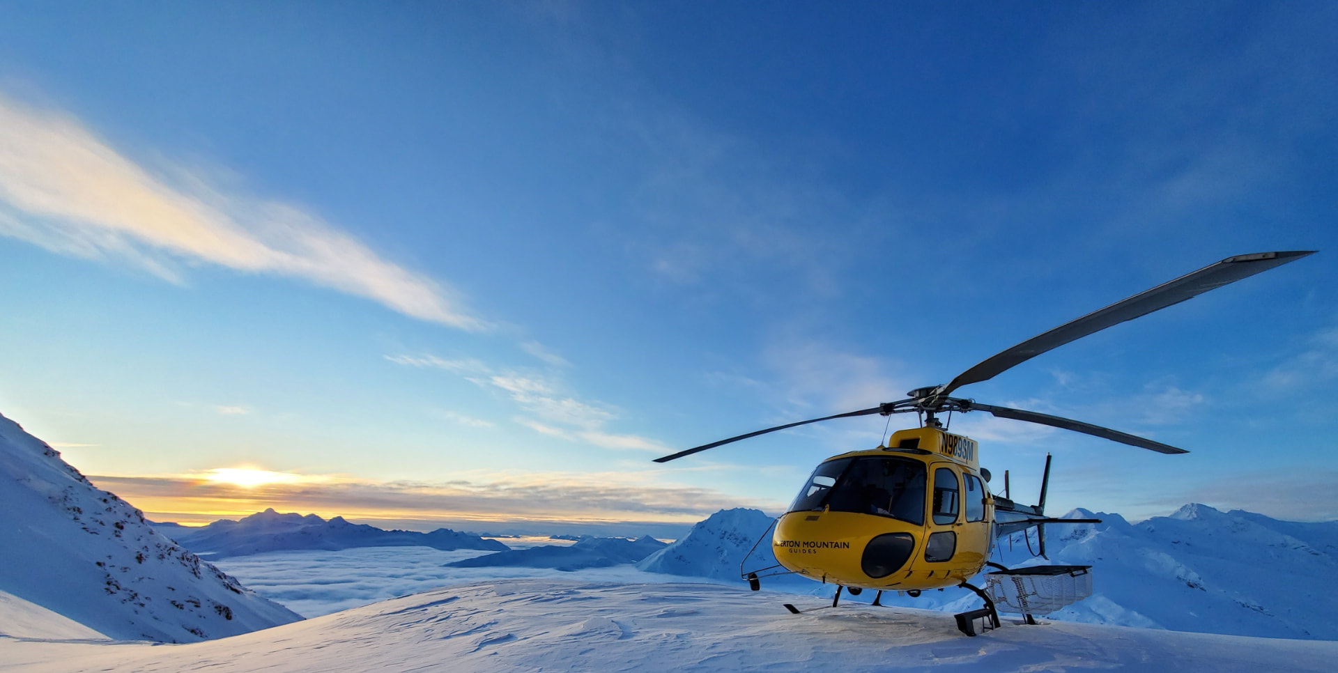 SMG helicopter at sunrise above a sea of clouds